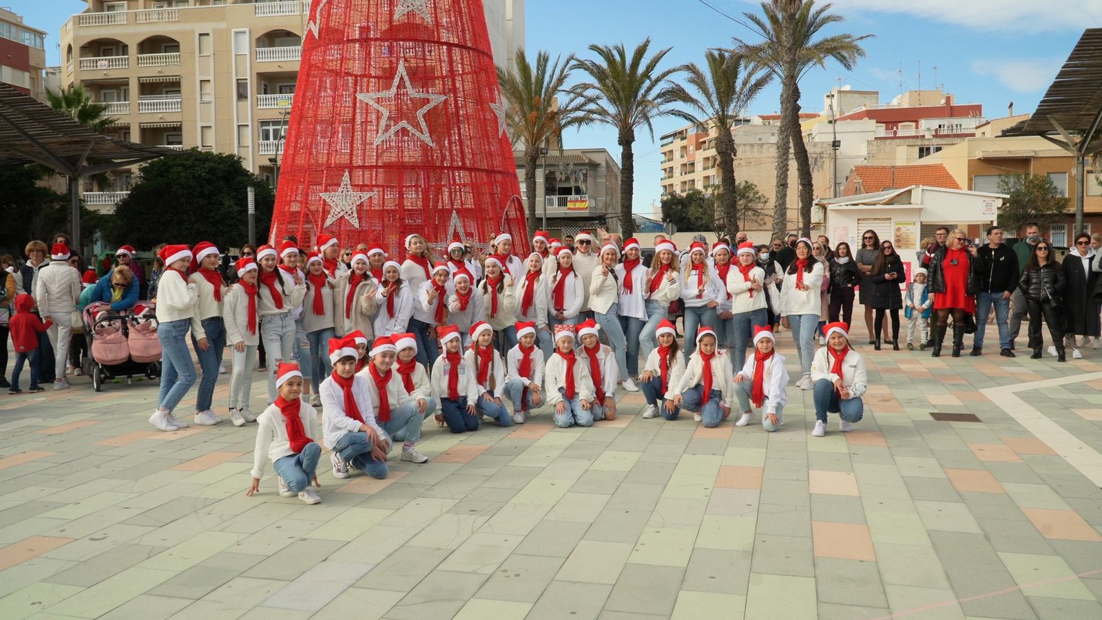Grupo de baile infantil posando frente al árbol rojo